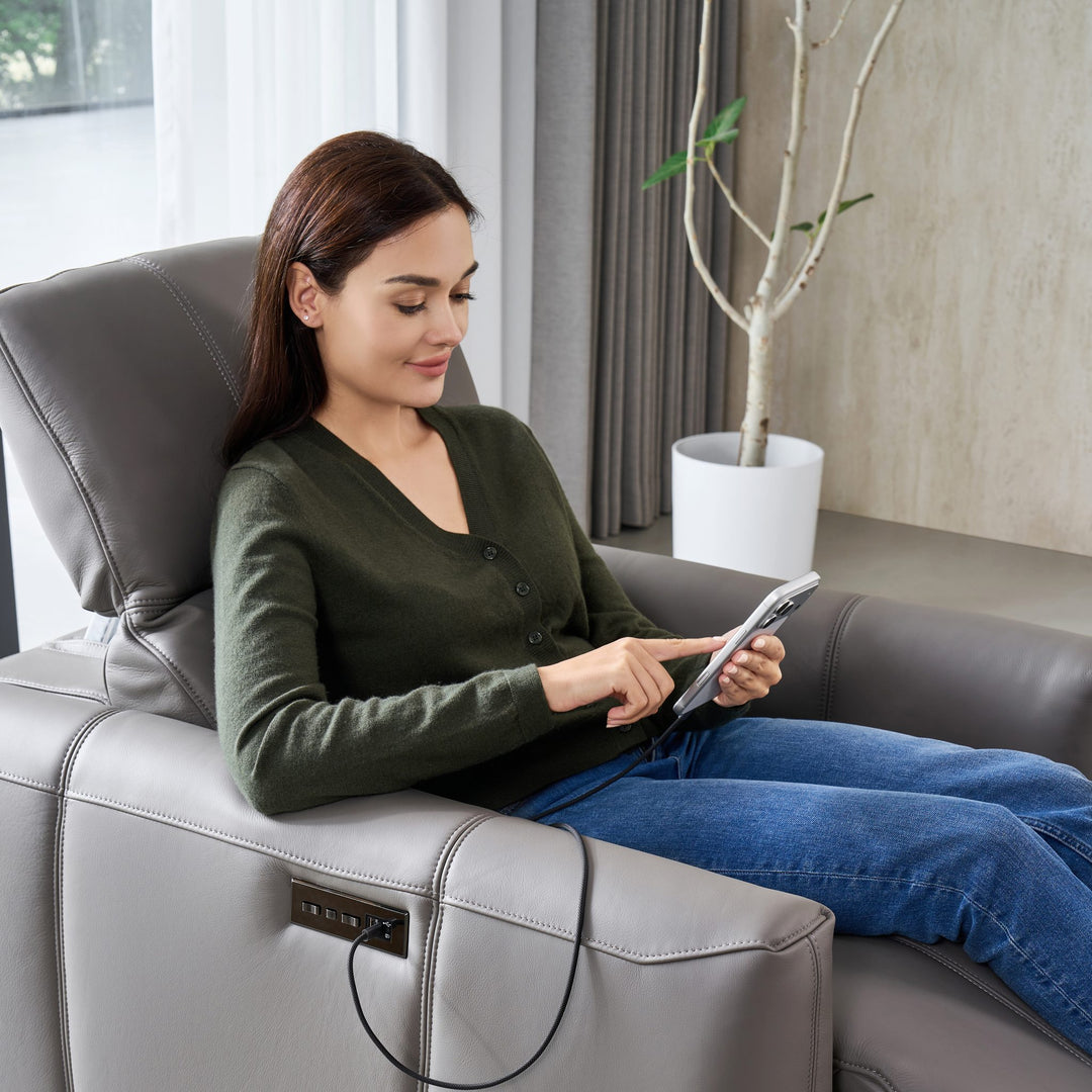 Woman reclined in the Bailey 1 Seat Armchair, charging a tablet from the side panel