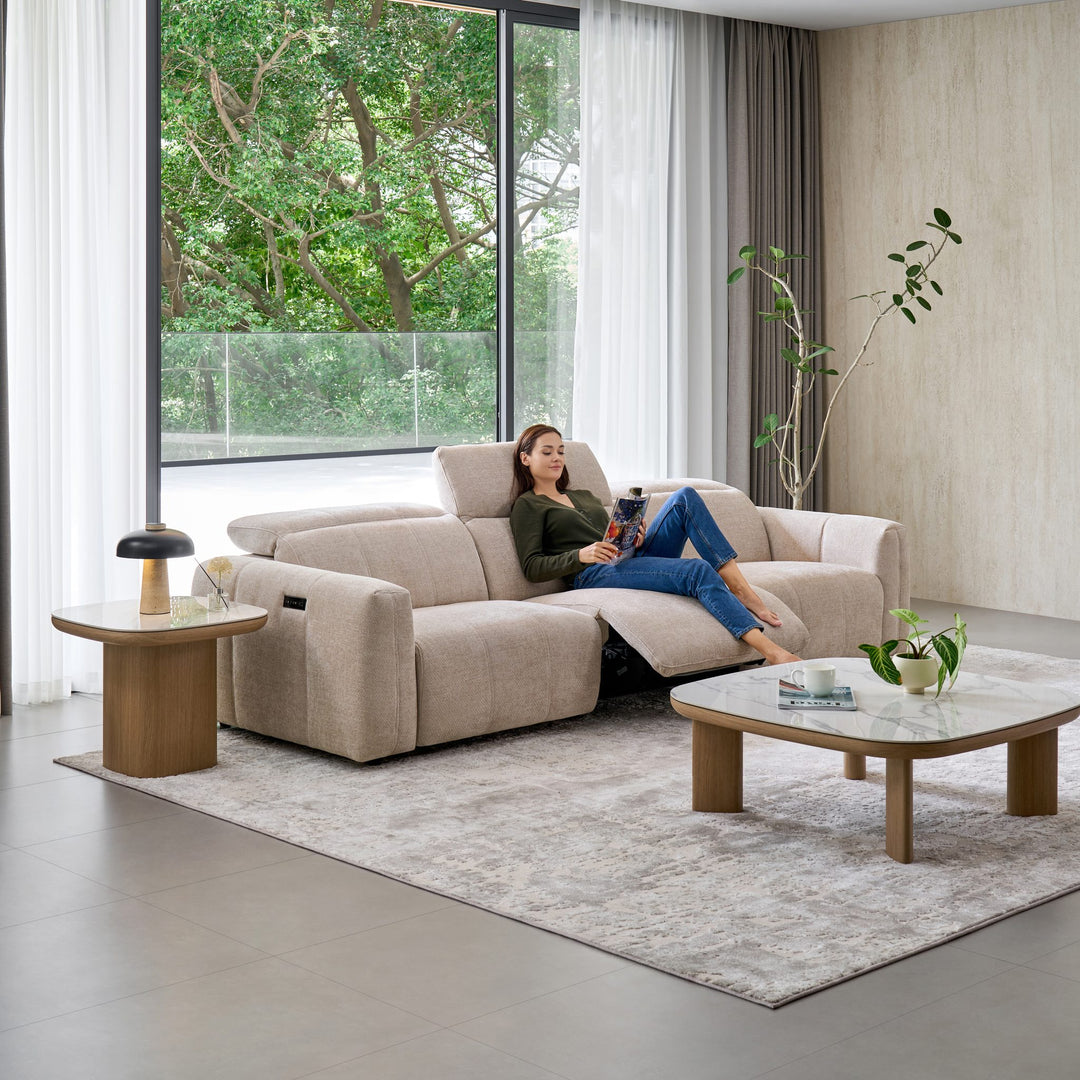 Woman relaxing on the Bailey 2 Seat Sofa in beige fabric with one seat reclined