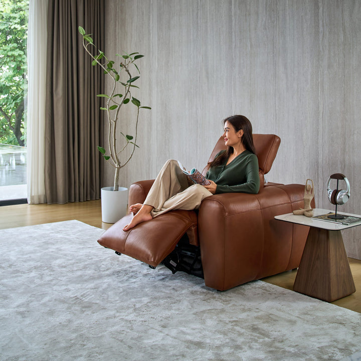Woman reading in a reclined Cambridge armchair in tan leather