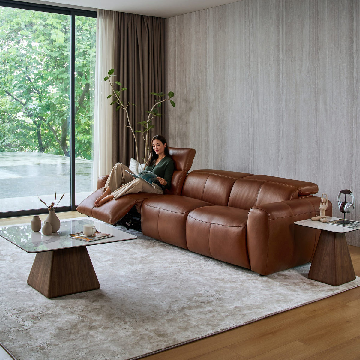 Woman relaxing on a reclined seat of the Cambridge 3 seat sofa in tan leather