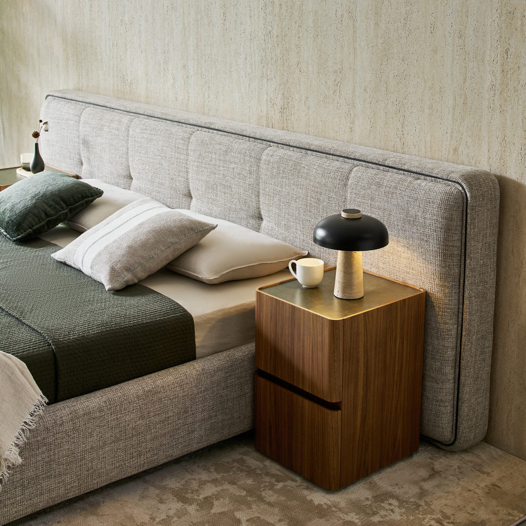 Clara Bed headboard extending behind a walnut Persia bedside table