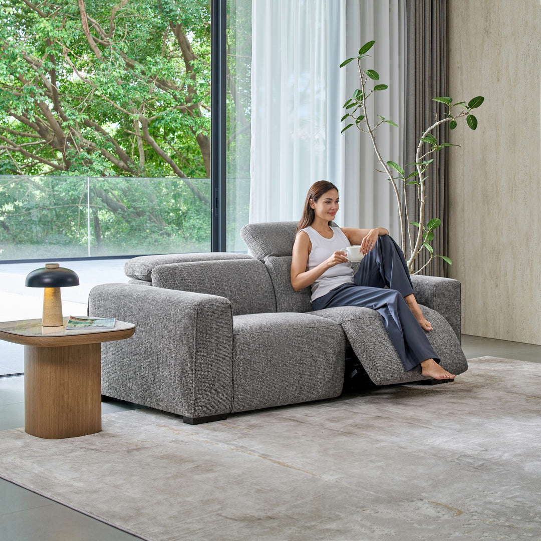 Woman reclining on the Jeddah 2 seat sofa in grey fabric