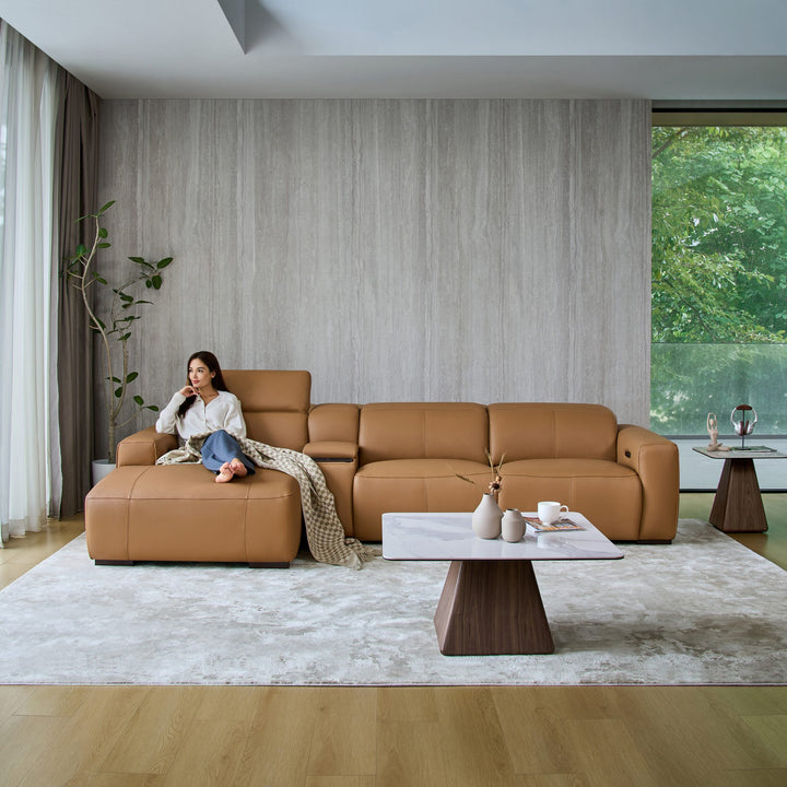 Woman relaxing on the chaise of the Jeddah sofa in tan leather